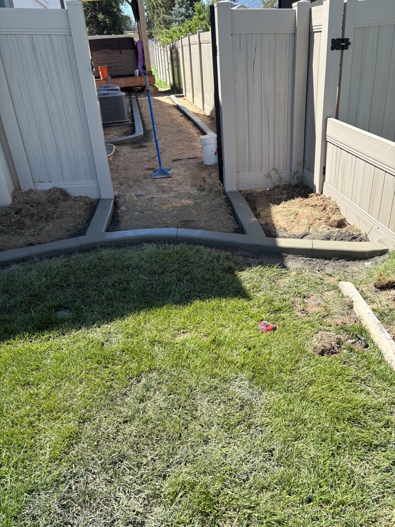 Curved backyard concrete curbing defining mulched flower beds and lawn boundaries in a Utah residential backyard.